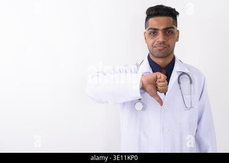 Studio shot of young Indian man doctor giving Thumbs down against white background Banque D'Images