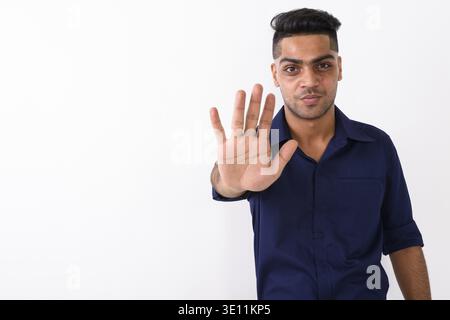 Studio shot of young businessman showing Indiens geste d'arrêt contre fond blanc Banque D'Images