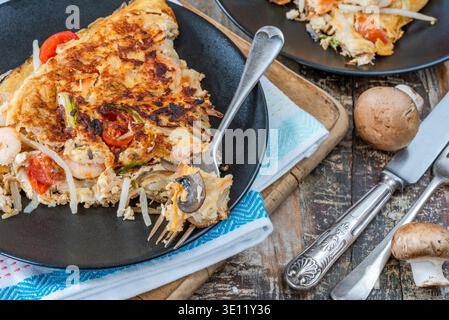 Omelette salée avec crevettes, saumon fumé, champignons, tomates, oignons de printemps et beansprouts Banque D'Images