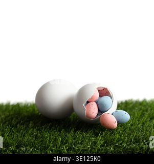 Composition de Pâques avec de petits oeufs peints dans un oeuf de poule blanc éclos sur une pelouse verte. Décor festif de Pâques isolé sur un fond blanc. Copier s Banque D'Images