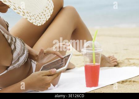 La jeune femme utilise un PC tablette sur la plage Banque D'Images