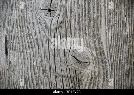 Gros plan de la texture du bois altérée présentant des motifs de grain et des nœuds. C'est une toile de fond rustique, vieillie et détaillée Banque D'Images