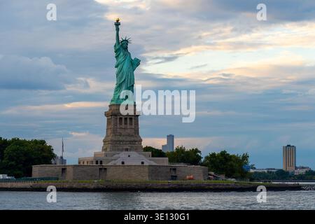 Liberty Island et Statue de la liberté vue depuis l'eau au coucher du soleil, New York City, États-Unis. Banque D'Images