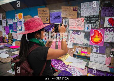 MEXICO, MEXIQUE - 8 MARS 2026 : une jeune femme photographie des panneaux de protestation sur la place principale de Mexico. 8M mars 2026 Banque D'Images