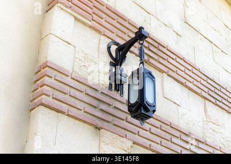 Lampe suspendue à un mur. La lampe est noire et blanche. Le mur est fait de briques Banque D'Images