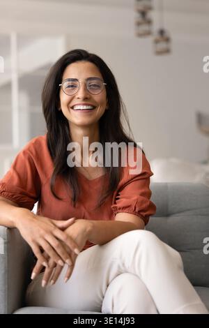 Femme confiante assise dans un fauteuil souriant à la caméra Banque D'Images
