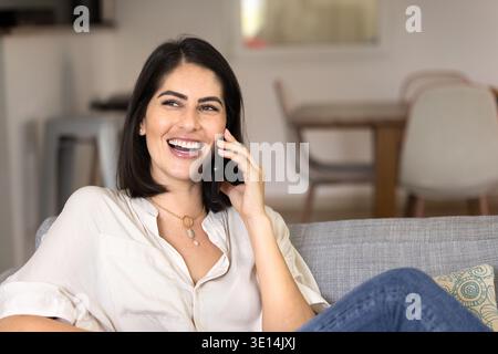 Heureuse jeune femme hispanique détendue parlant au téléphone portable Banque D'Images
