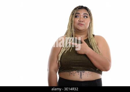 Studio shot of young Asian woman looking fat et montre de l'index sur le côté Banque D'Images