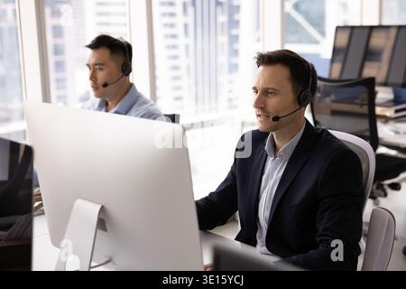 Les consultants en assistance virtuelle utilisent des casques et des oreillettes pour regarder les écrans de pc Banque D'Images