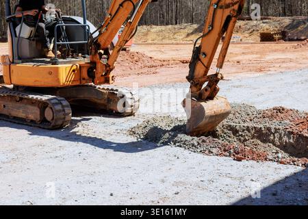 Le travailleur utilise une excavatrice pour creuser une tranchée sur le chantier de construction Banque D'Images