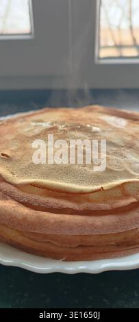 Une haute pile de fines crêpes dorées sur une assiette sur un fond sombre. pile de crêpes, petit déjeuner traditionnel, vacances maslenitsa. Maslenitsa. Banque D'Images