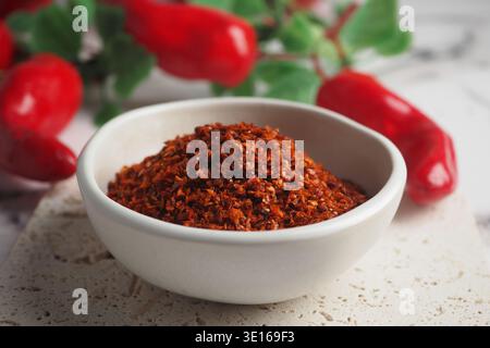 Flocons de piment rouge épicés dans un bol blanc sur une table Banque D'Images