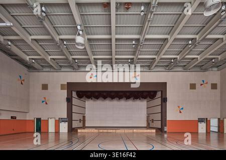 Gymnase scolaire vide avec sol poli et scène. Banque D'Images