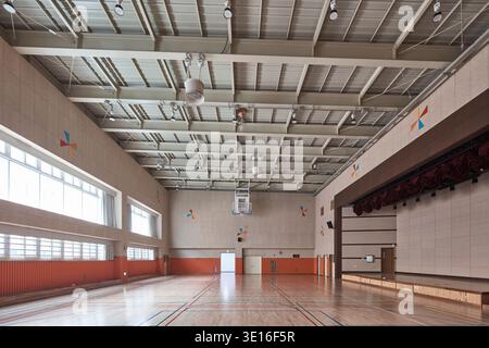 Gymnase scolaire vide avec sol poli et scène. Banque D'Images