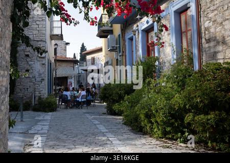 Groupe d'amis se relaxant dans un charmant café en plein air sur une rue pavée dans le village traditionnel de Pano lefkara, village de Chypre Banque D'Images