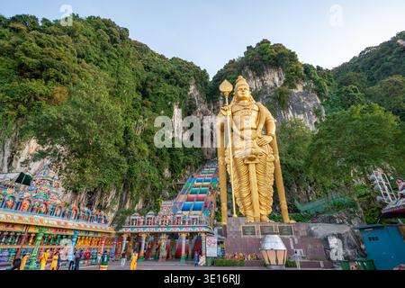 Grottes de Batu, Selangor/Malaisie – 3 février 2020 : les visiteurs traversent le complexe du temple sous les falaises calcaires près de la statue dorée. Banque D'Images