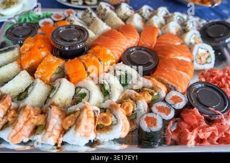 Une vue rapprochée d'un grand plateau de sushis assorti présentant différents types de cuisine japonaise. L'arrangement comprend des tranches de sashimi de saumon frais, Banque D'Images