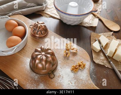 Préparation de cuisson avec des moules en cuivre vintage, des œufs et des noix sur une planche de bois. Plan à angle élevé de la table de cuisine rustique avec cuivre antique Banque D'Images