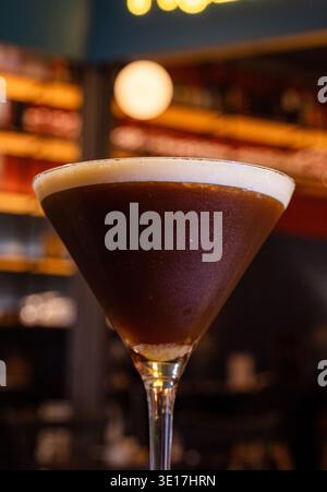 Un martini expresso sophistiqué dans un verre transparent, élégamment présenté sur un comptoir de bar. La couleur riche du café et la mousse crémeuse créent un et invitant Banque D'Images