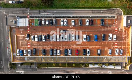 Drone capture une vue aérienne d'un parking occupé à Cingoli, en Italie. Les véhicules modernes sont soigneusement disposés en rangées, mettant en évidence la planification urbaine et sp Banque D'Images