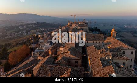 Une vue imprenable par drone de Cingoli, en Italie, capturant l'architecture charmante de la ville et les collines ondulantes baignées dans la lueur chaude du coucher du soleil, transportant Banque D'Images