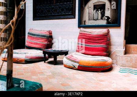 Intérieur marocain captivant présentant un riad joliment décoré à Marrakech. Comprend des coussins traditionnels colorés et une atmosphère sereine emb Banque D'Images