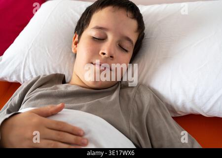 D'en haut de la récolte anonyme mâle en pyjama couché dans le lit sous une couverture chaude et dormant à la chambre Banque D'Images