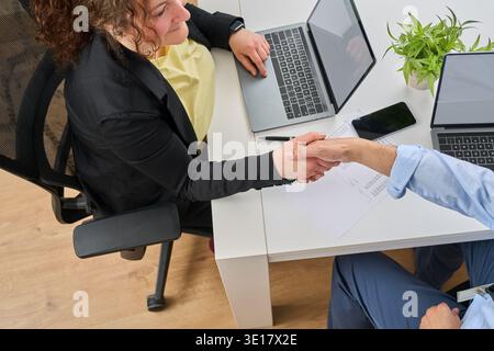 Prise de vue en grand angle de deux hommes d'affaires qui se secouent la main dans un bureau Banque D'Images