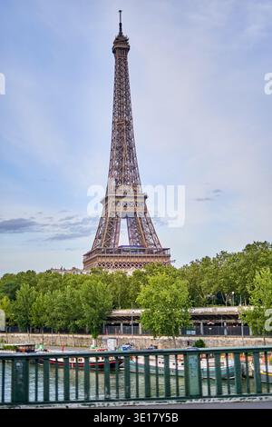La Tour Eiffel se dresse majestueusement contre un ciel partiellement nuageux, vu de l'autre côté de la Seine à Paris, en France. Le treillis de fer emblématique... Banque D'Images