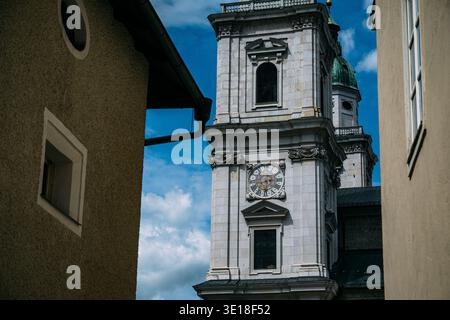Tour de la cathédrale de Salzbourg avec cadran d'horloge vue entre les vieux bâtiments par une journée ensoleillée Banque D'Images