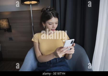 Jeune femme hispanique américaine Gen Z utilisant smartphone dans le concept de technologie moderne Banque D'Images