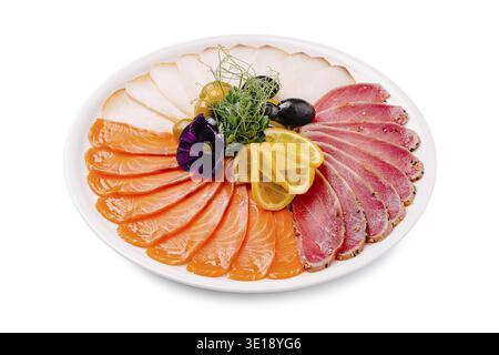 Un plat magnifiquement arrangé avec du saumon finement coupé en tranches, du thon en croûte de poivre et des tranches de viande blanche, garni de tranches de citron, noir et gree Banque D'Images