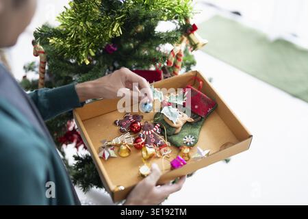 Mains heureuses décorant l'arbre de Noël pour les vacances de Noël Banque D'Images
