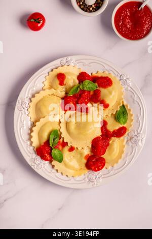 Raviolis avec sauce tomate et basilic sur assiette blanche. Banque D'Images