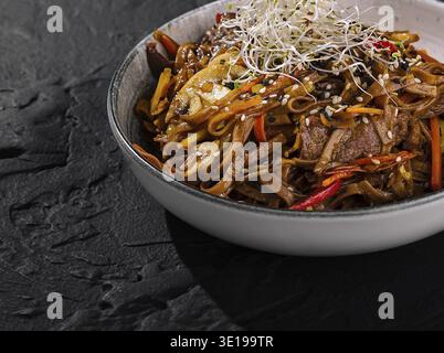 Sauté de bœuf salé avec nouilles et légumes croquants, garni de pousses Banque D'Images