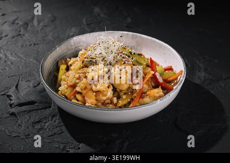 Délicieux riz frit aux crevettes avec légumes frais et pousses, servi dans un bol élégant Banque D'Images