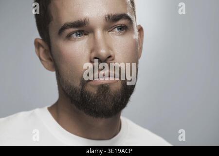 Portrait de jeune et beau homme barbu avec la peau propre sur fond gris Banque D'Images