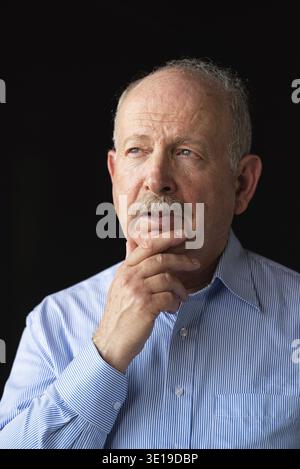 Homme âgé à cheveux gris avec moustache portant des lunettes et pensant à la verticale Banque D'Images