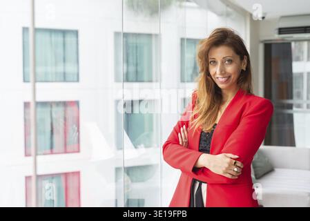 Portrait d'une belle femme d'affaires au bureau portant une veste de costume rouge Banque D'Images