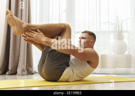 Jeune et musclé homme faisant des exercices d'abs pendant l'entraînement intense à la maison Banque D'Images