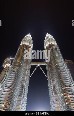 Low Angle View Of Les célèbres tours Petronas Towers de nuit à Kuala Lumpur, Malaisie Shot verticale Banque D'Images