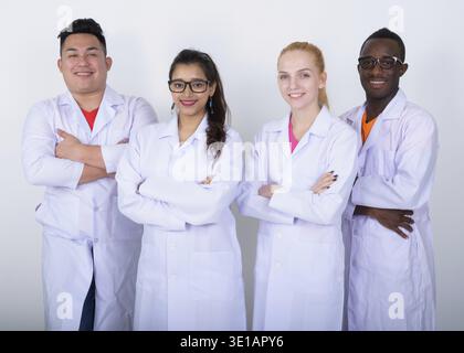 Studio shot of happy groupe diversifié de multi ethnic doctors smiling with arms crossed ensemble Banque D'Images