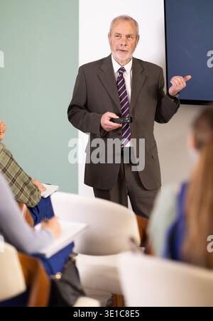 Professeur senior parlant aux élèves en salopette bleue Banque D'Images