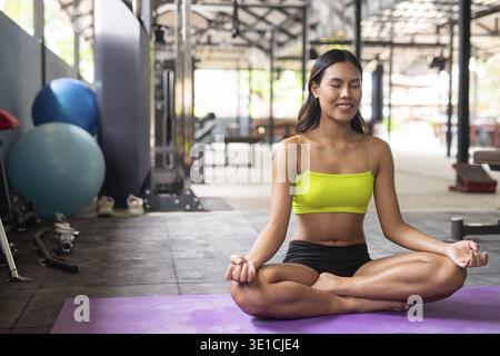 Jeune belle femme asiatique au gymnase faisant du yoga Banque D'Images