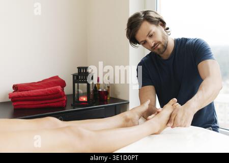 Professionnel beau masseur barbu homme pendant le massage des pieds féminins Banque D'Images