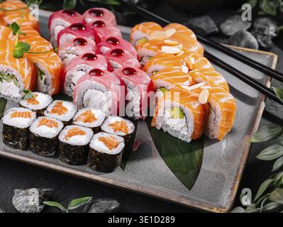Ensemble de sushis élégant avec divers rouleaux et sashimi sur une assiette moderne avec des garnitures Banque D'Images