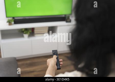 Femme âgée regardant la télévision intelligente et utilisant la télécommande main tenant la télévision audio télécommande Moyen âge asiatique film série de télévision Banque D'Images