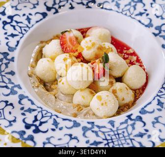 Salade de fruits colorée avec boulettes de melon et tranches de fraises, servie dans un bol orné de gros plan Banque D'Images