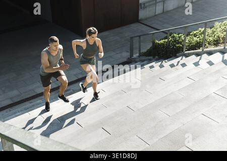 Jeune couple sportif pendant la course d'escalier d'entraînement en plein air Banque D'Images