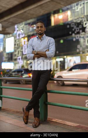 Portrait pleine longueur du bel homme d'affaires noir africain à l'extérieur dans la ville à la nuit verticale prise de vue Banque D'Images